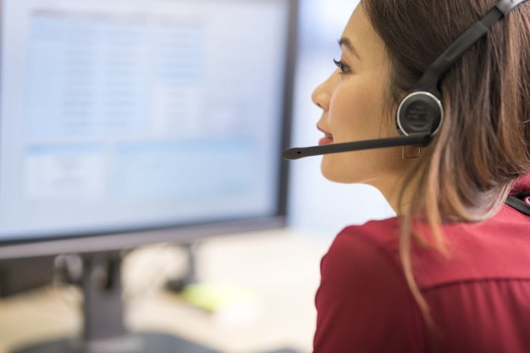 Close-up of customer service representative wearing wireless headset working in call centre.